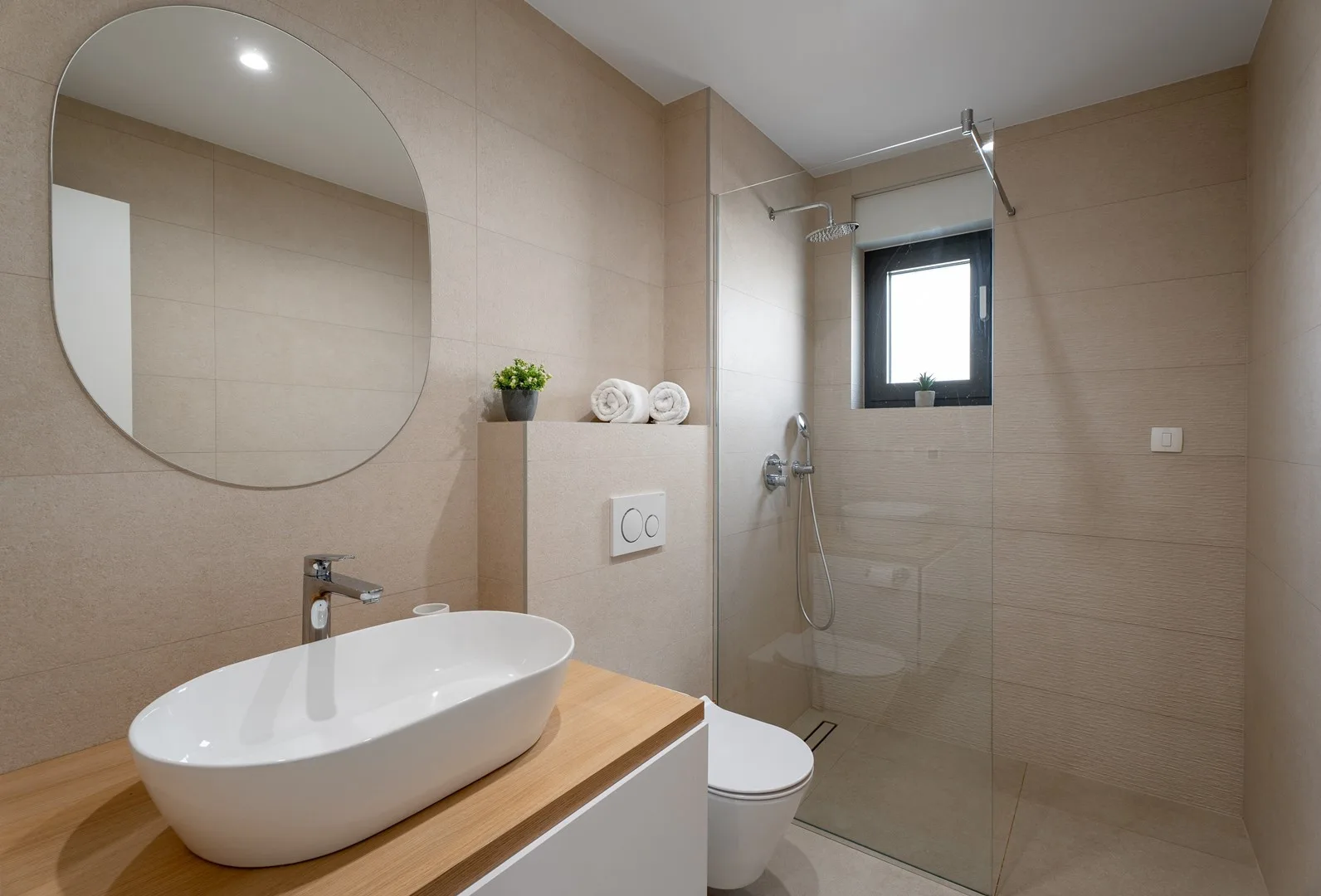 A tiled bathroom with a sink, toilet, and glass shower area.
