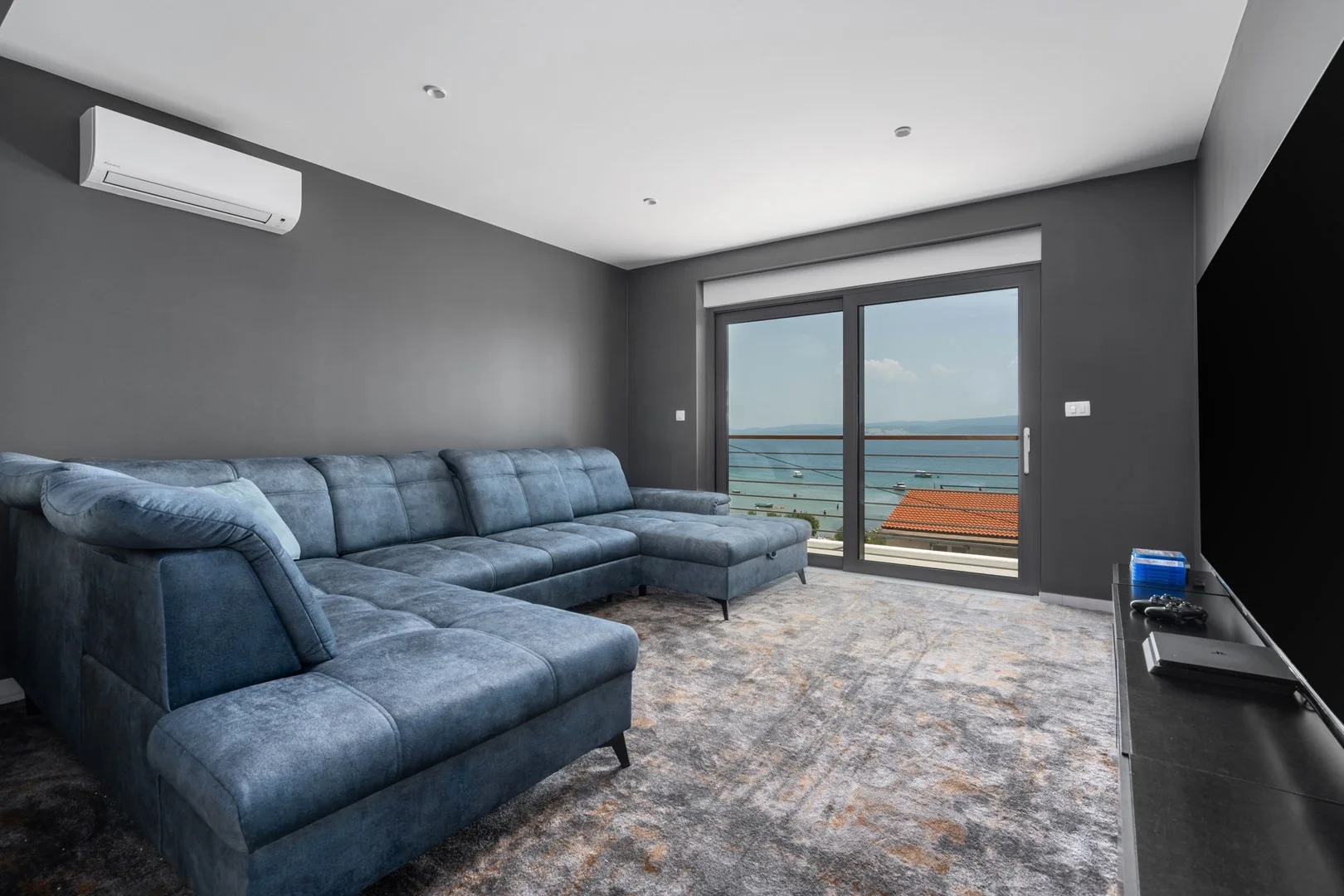 A living room with a sectional seating area facing glass doors and a sea view.