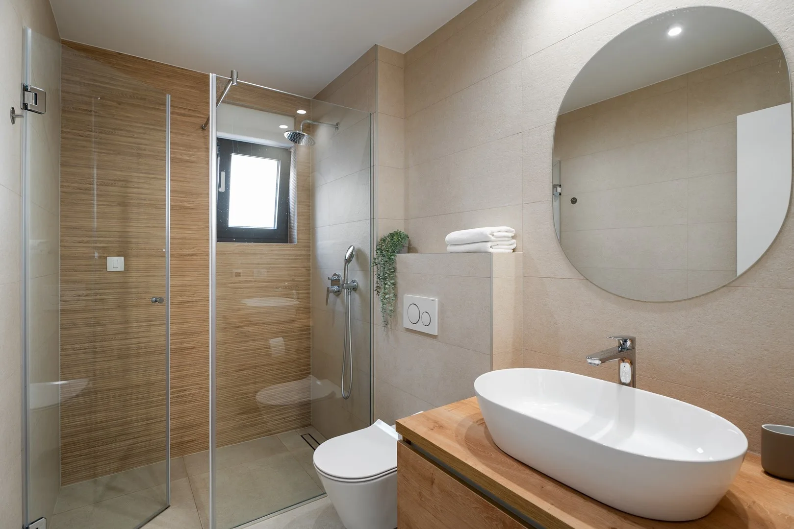 A modern bathroom with a glass shower, toilet, and vessel sink.