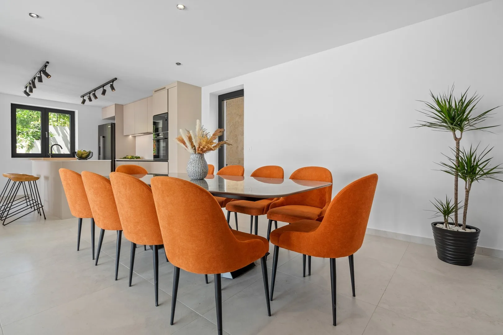 A dining area with orange seating around a table beside an open kitchen.
