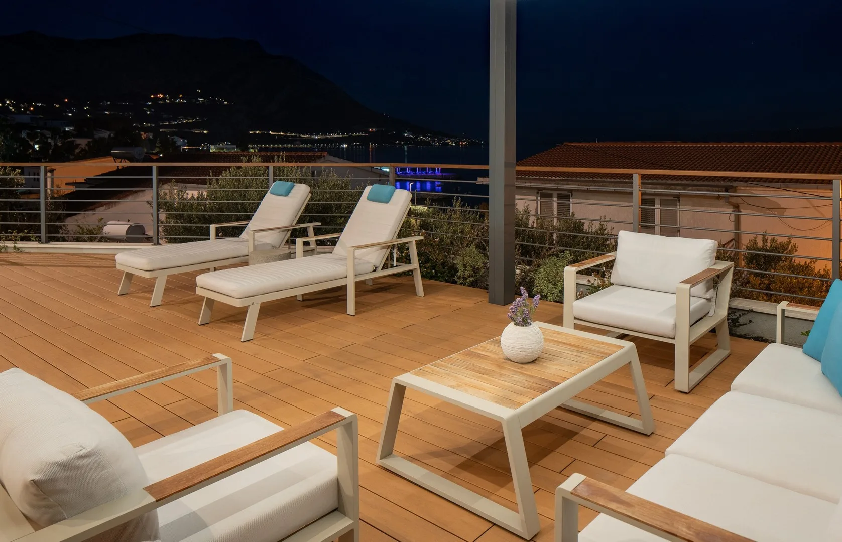 A rooftop terrace at night with outdoor seating and distant city lights.