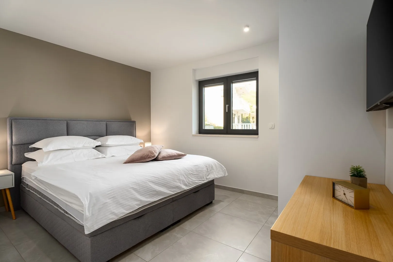 A bedroom with a large bed, a window, and a wooden dresser.