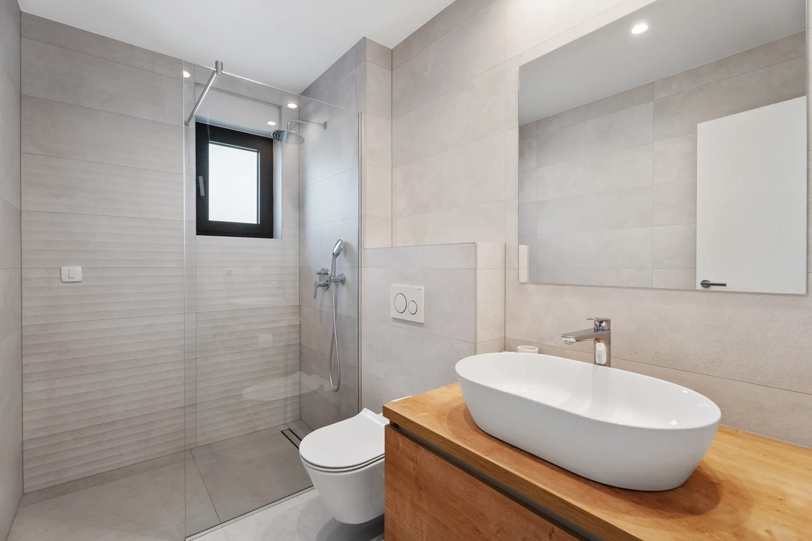 A modern bathroom with a glass shower, toilet, and vessel sink.