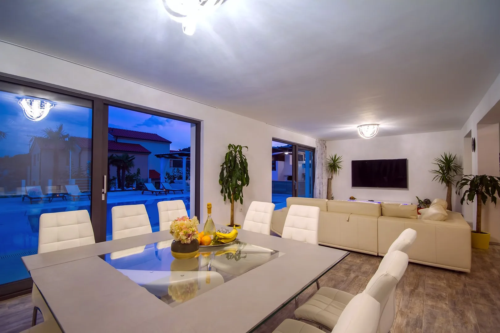 Sala de estar y comedor con mesa de vidrio y asientos junto a grandes ventanas.