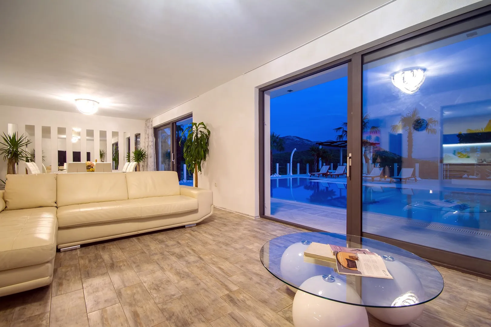 Una sala luminosa con asientos junto a grandes puertas de vidrio que dan a una piscina exterior.