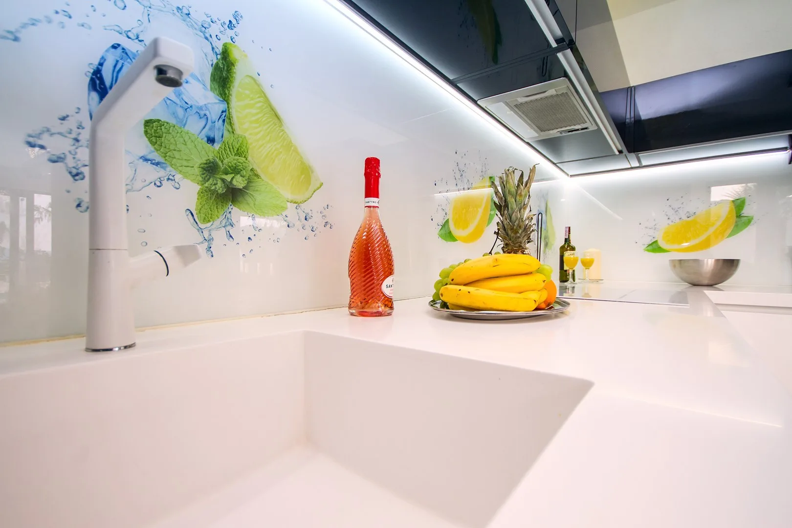 Una encimera luminosa de cocina con fregadero, fruta y un salpicadero colorido.