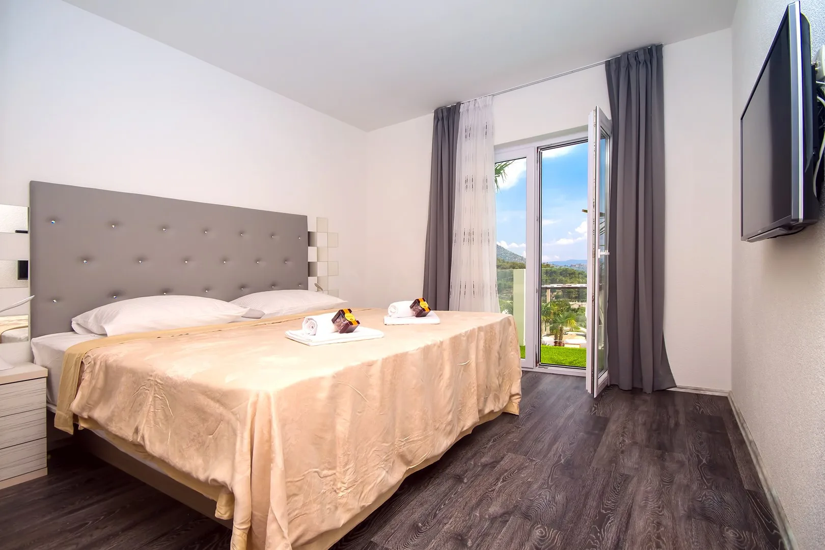 Un dormitorio con la cama tendida y la puerta del balcón abierta.