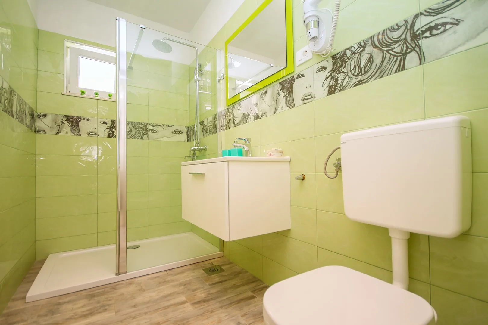 Un baño alicatado con una ducha de vidrio y un inodoro suspendido.