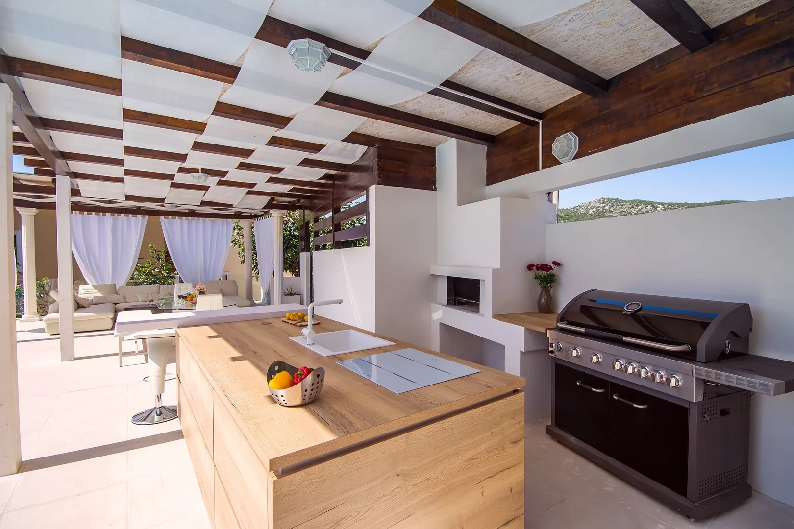 Una cocina al aire libre con una isla de madera y una parrilla empotrada.