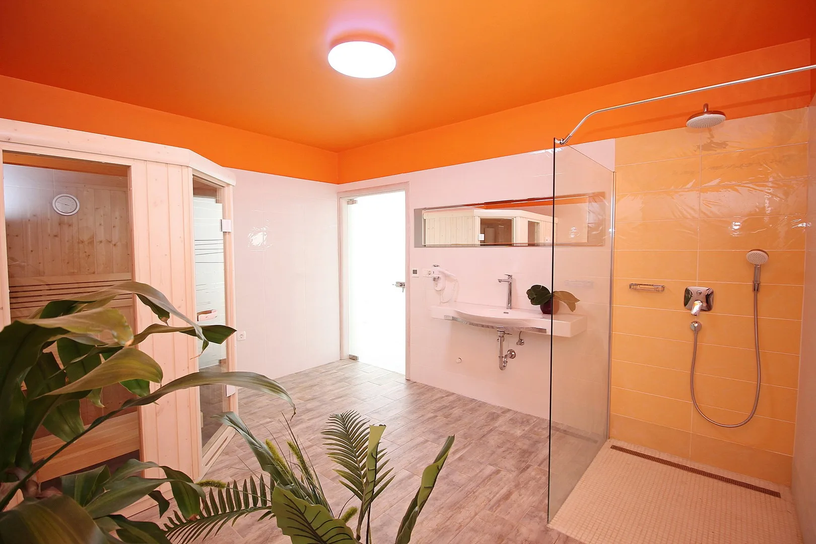 Un baño con ducha de vidrio, lavabo y sauna de madera.