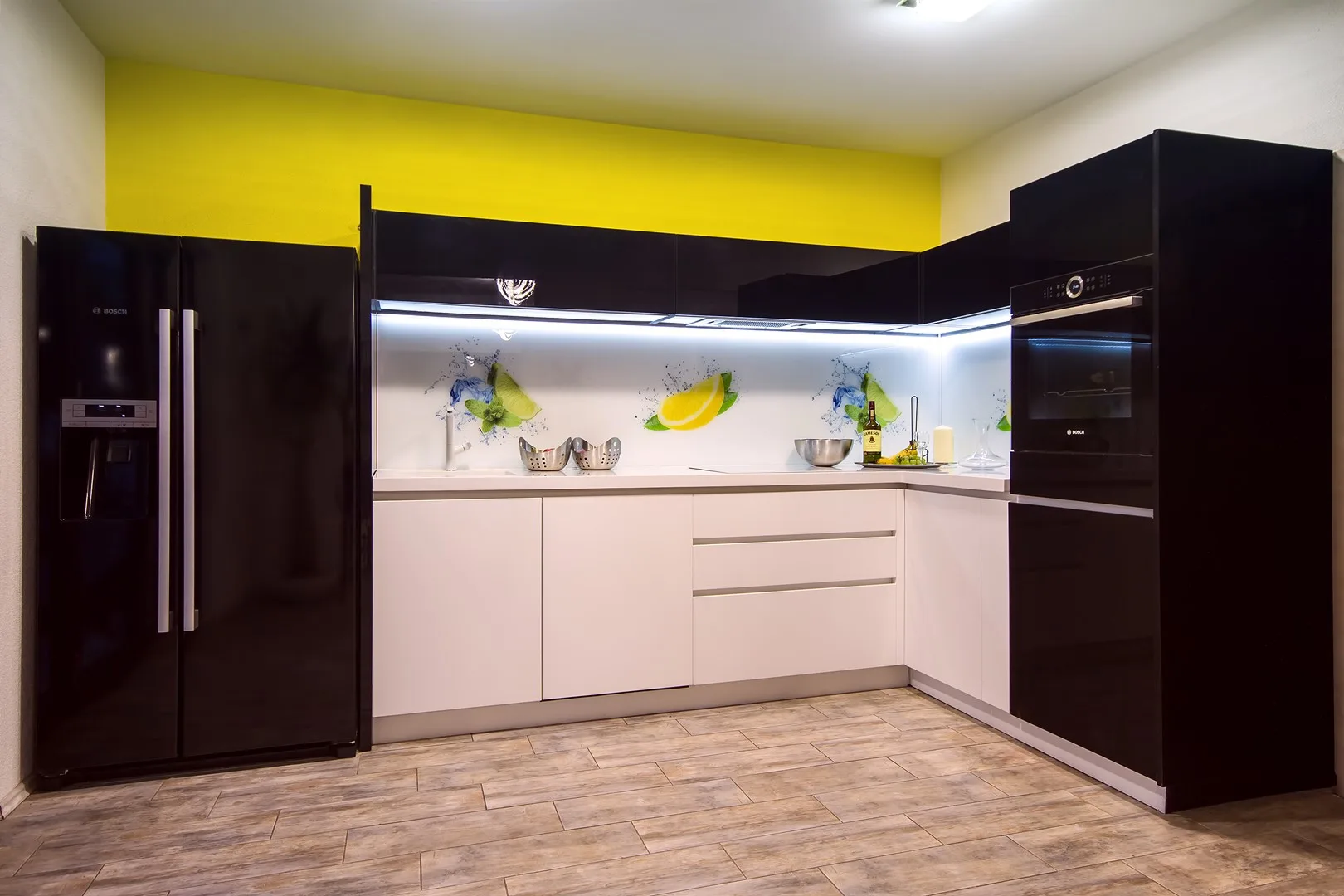 Cocina con gabinetes oscuros, gabinetes inferiores claros y una pared amarilla brillante.