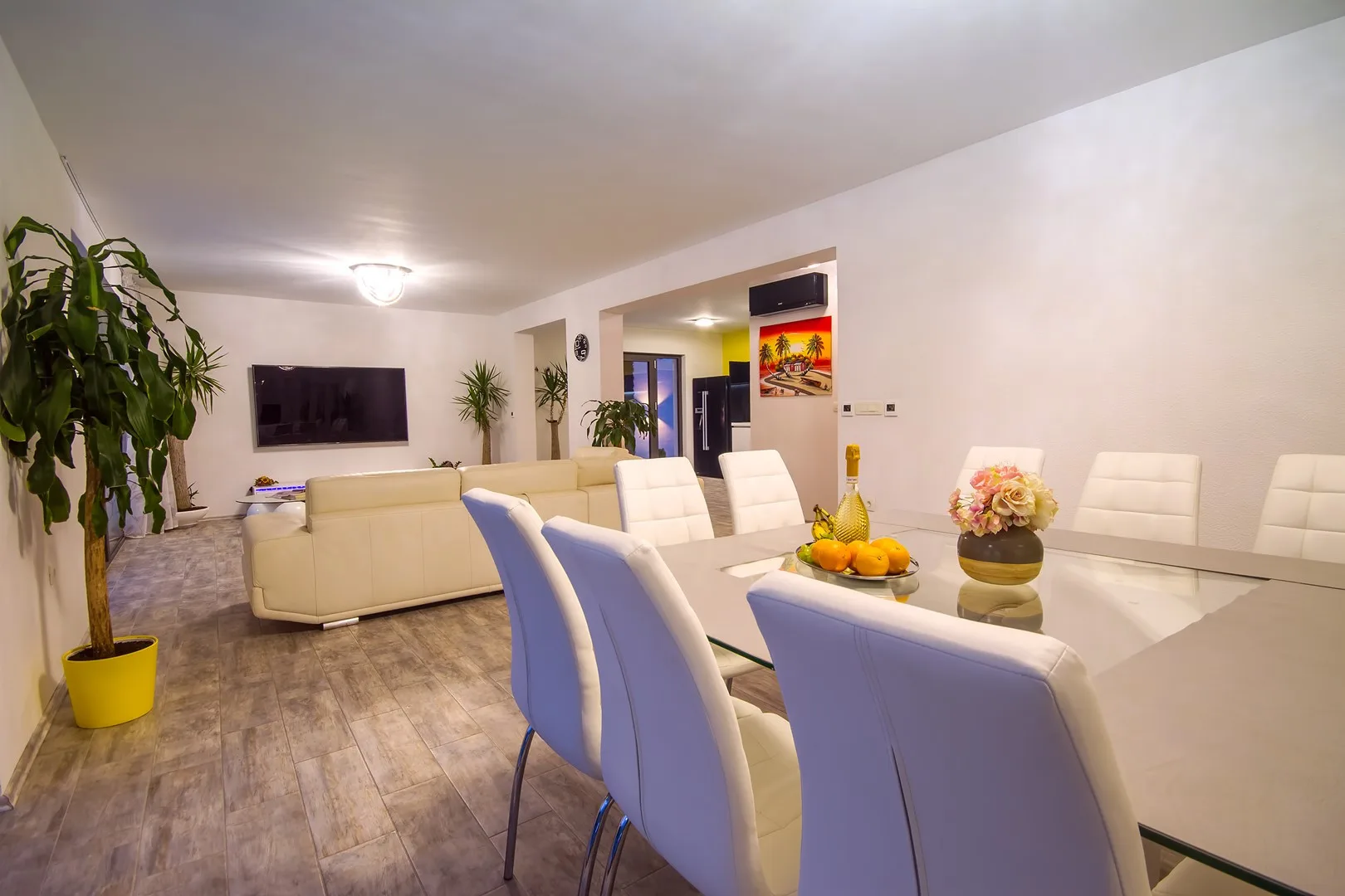 Un comedor luminoso con una mesa larga y asientos blancos junto a la sala de estar.