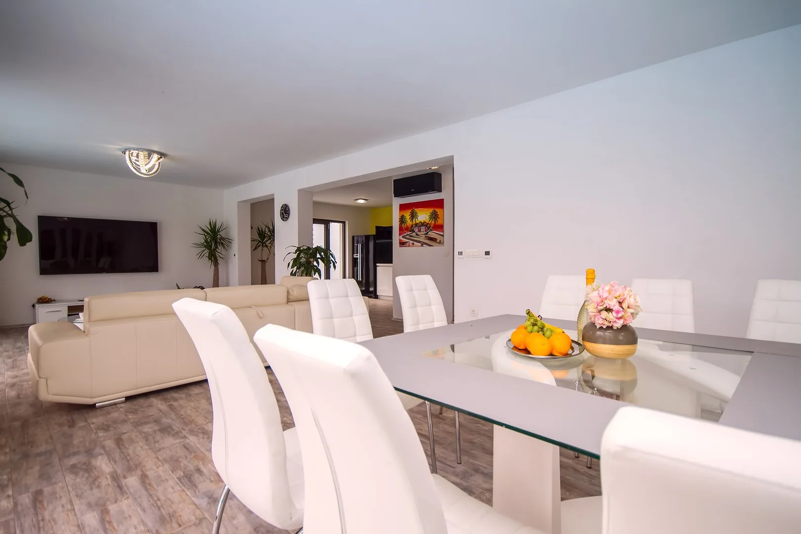Una luminosa sala de estar y comedor con mesa de vidrio y asientos blancos.