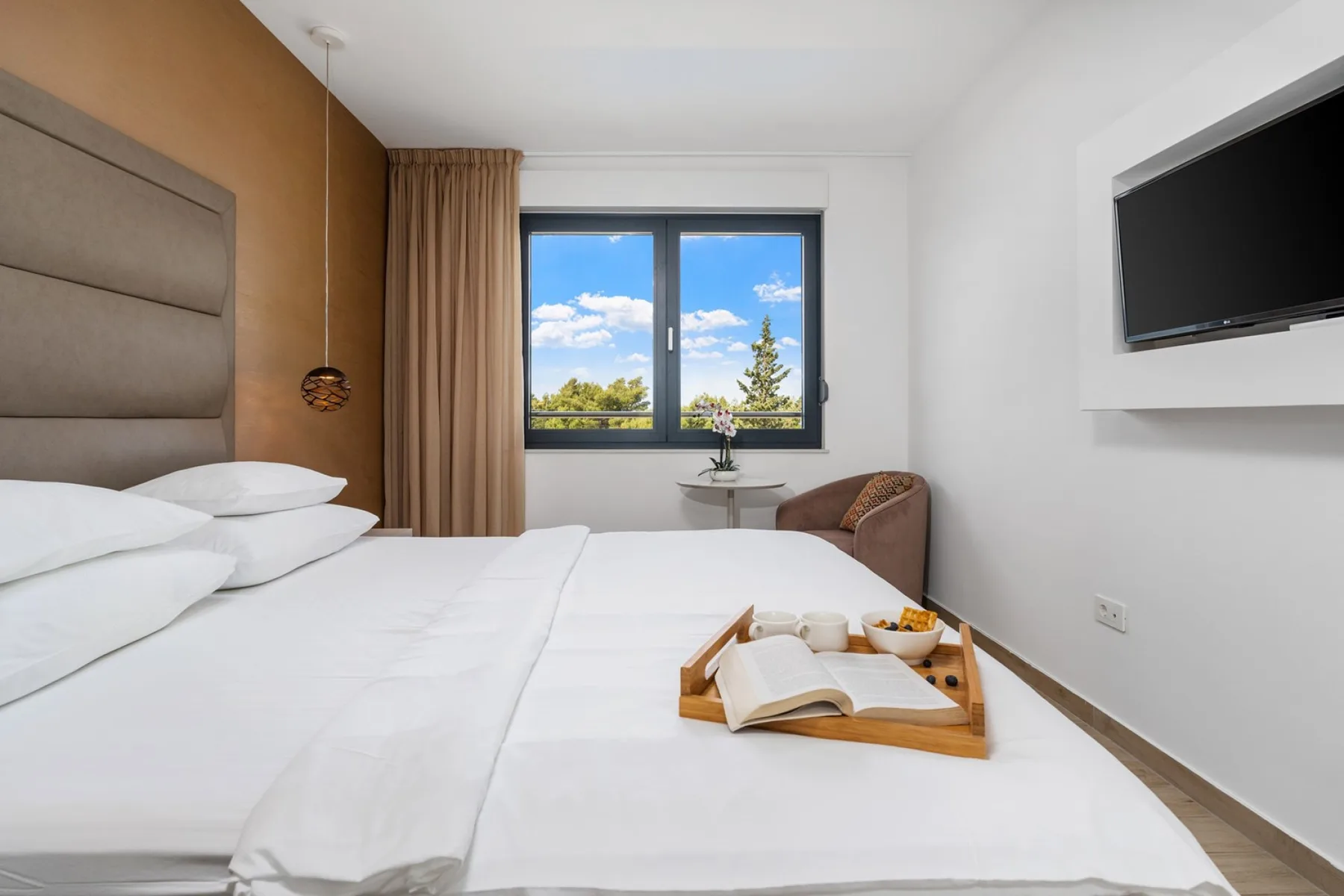 A bright bedroom with a neatly made bed and a large window.