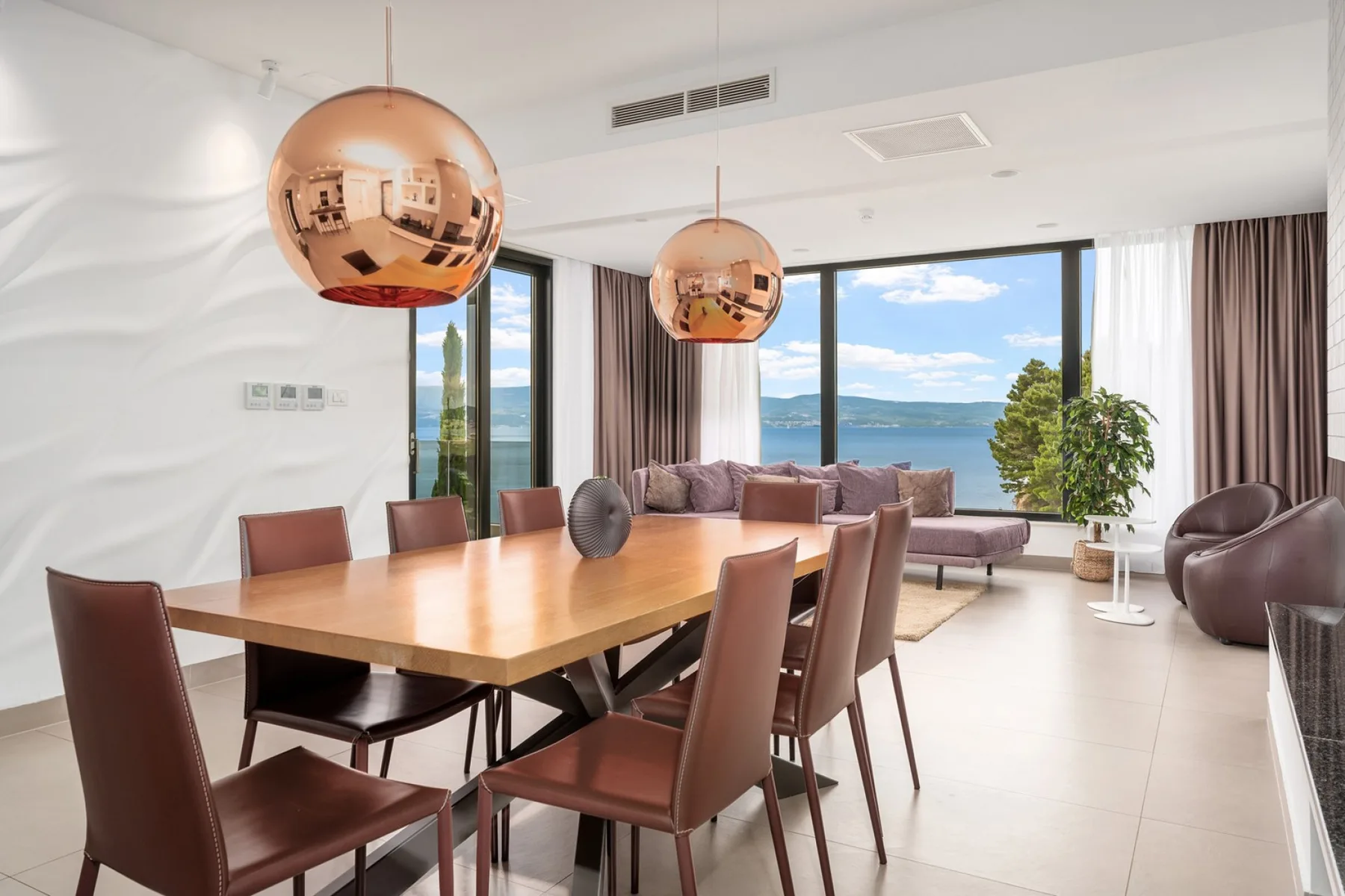 A dining area with a wooden table and large windows overlooking the water.