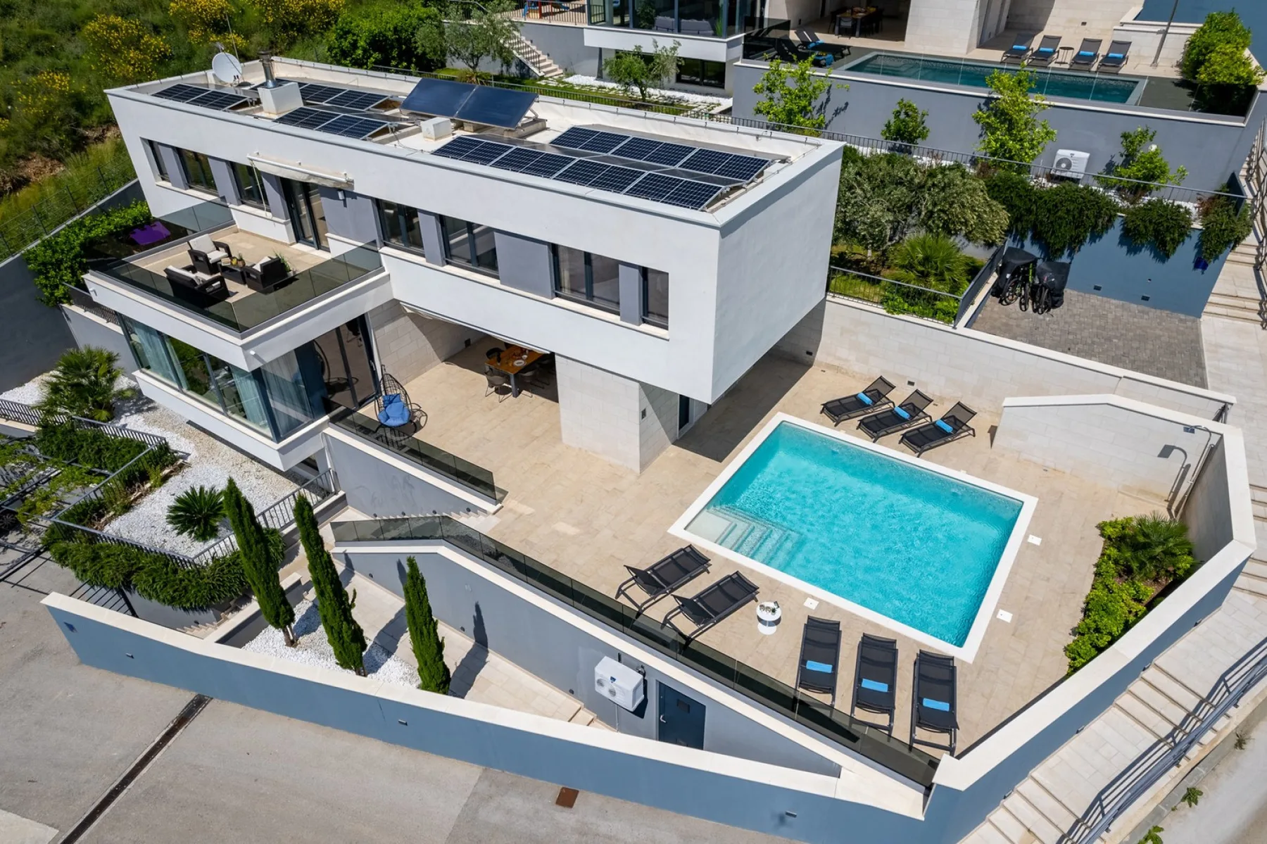 A modern house with a swimming pool and sun loungers on the terrace.