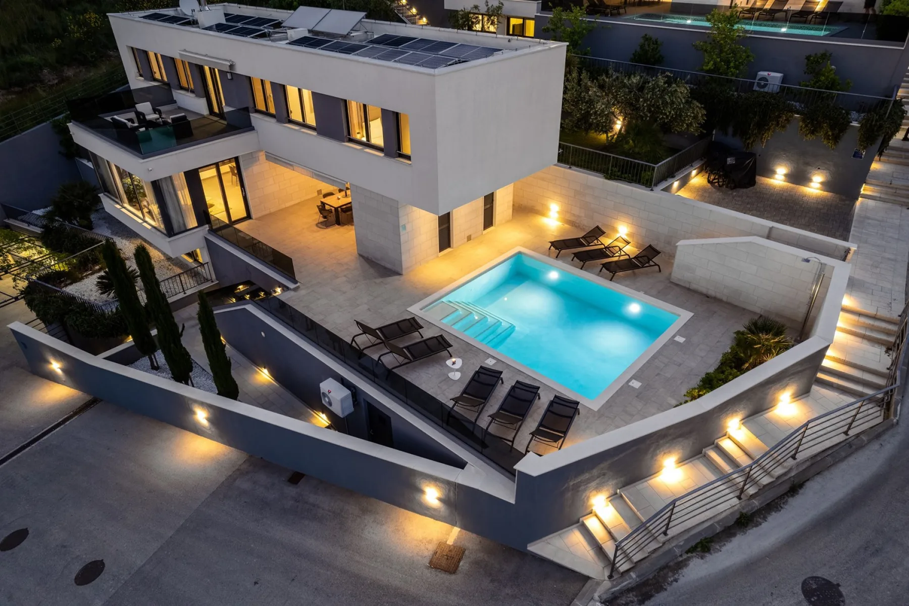 A modern house with a lit swimming pool and outdoor seating.