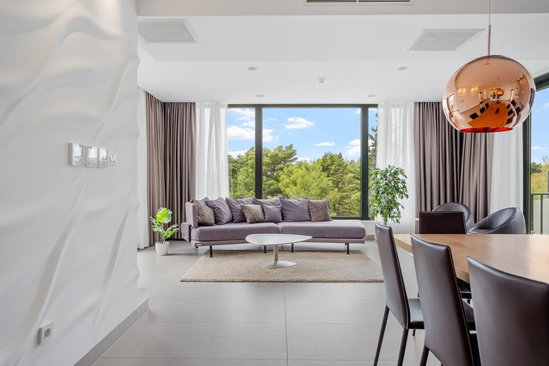 A bright living and dining area with a seating arrangement beside large windows.