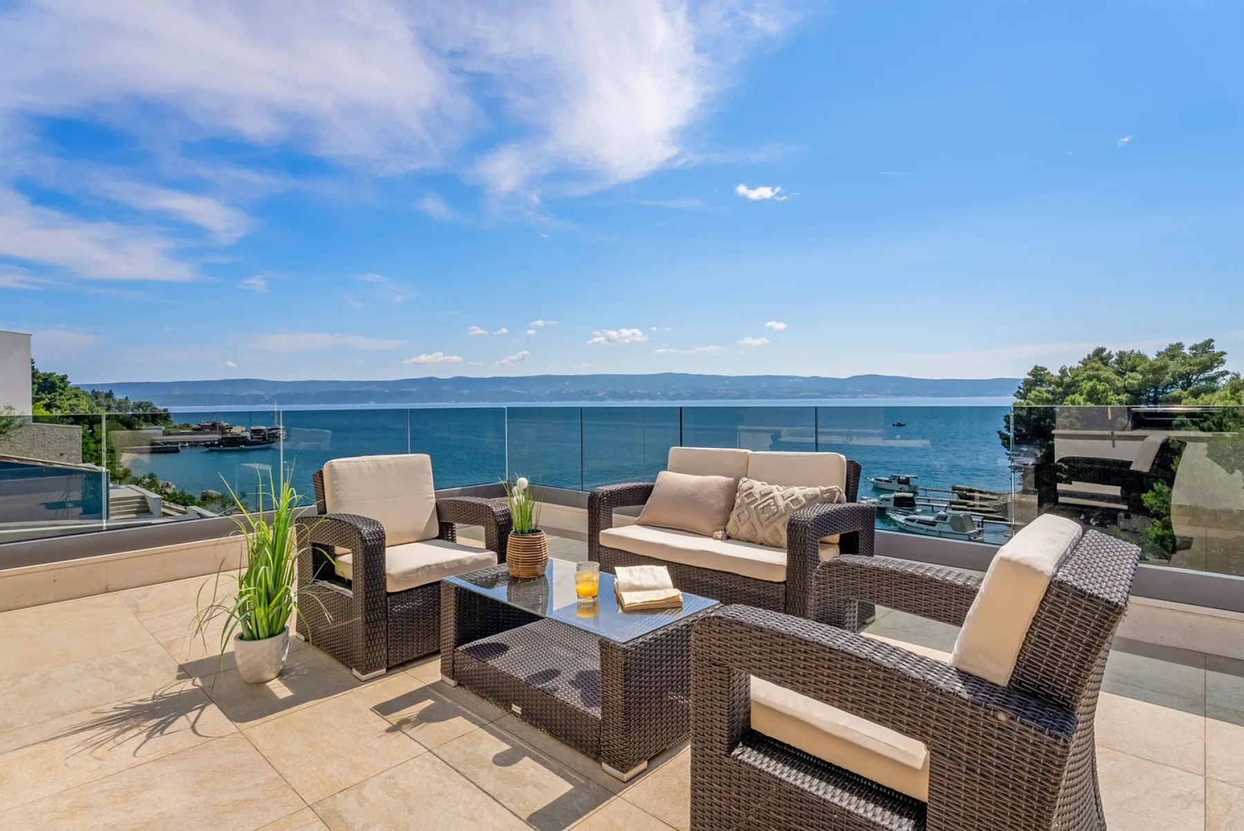 A waterfront terrace with cushioned seating and an open view of the water.