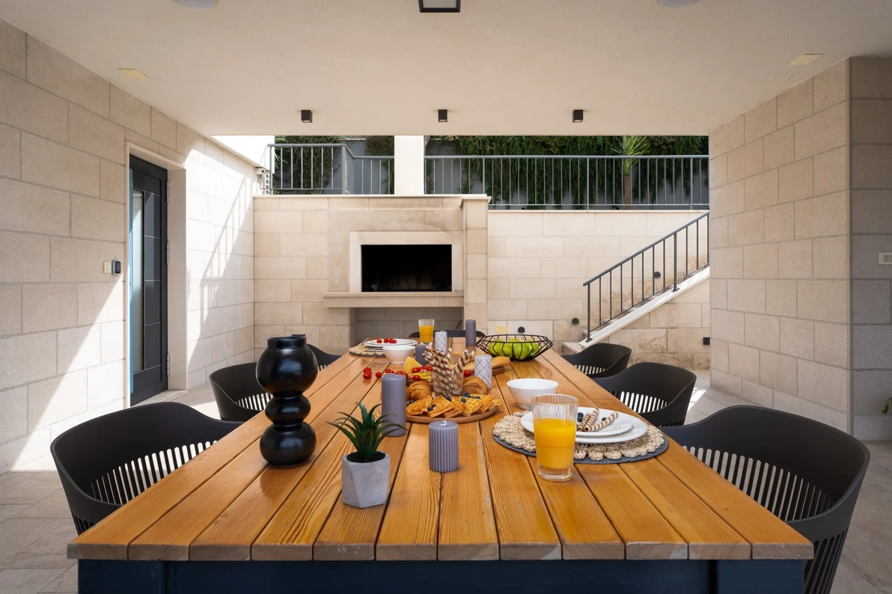 A covered dining area with a long table set with food and drinks.