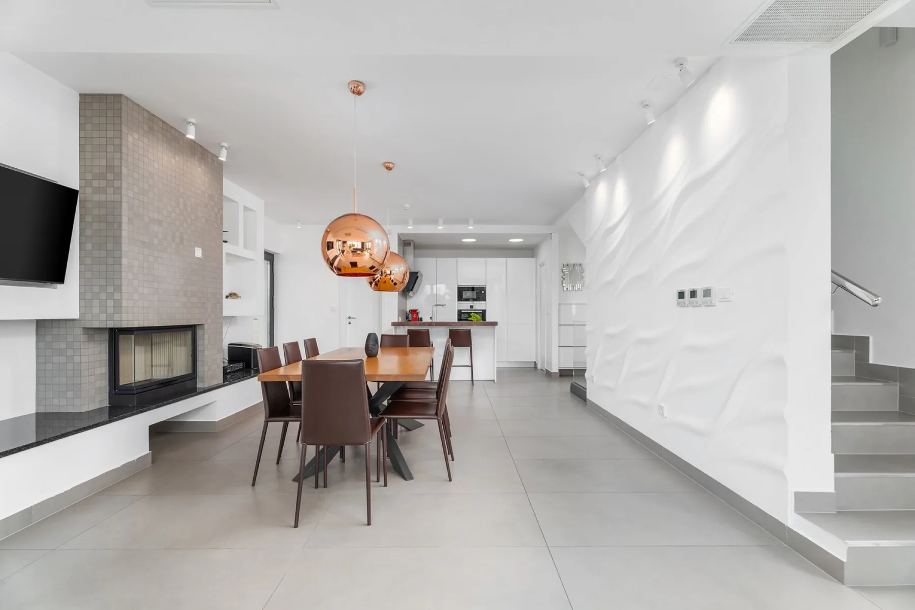A modern dining area with a table, seating, and a fireplace.