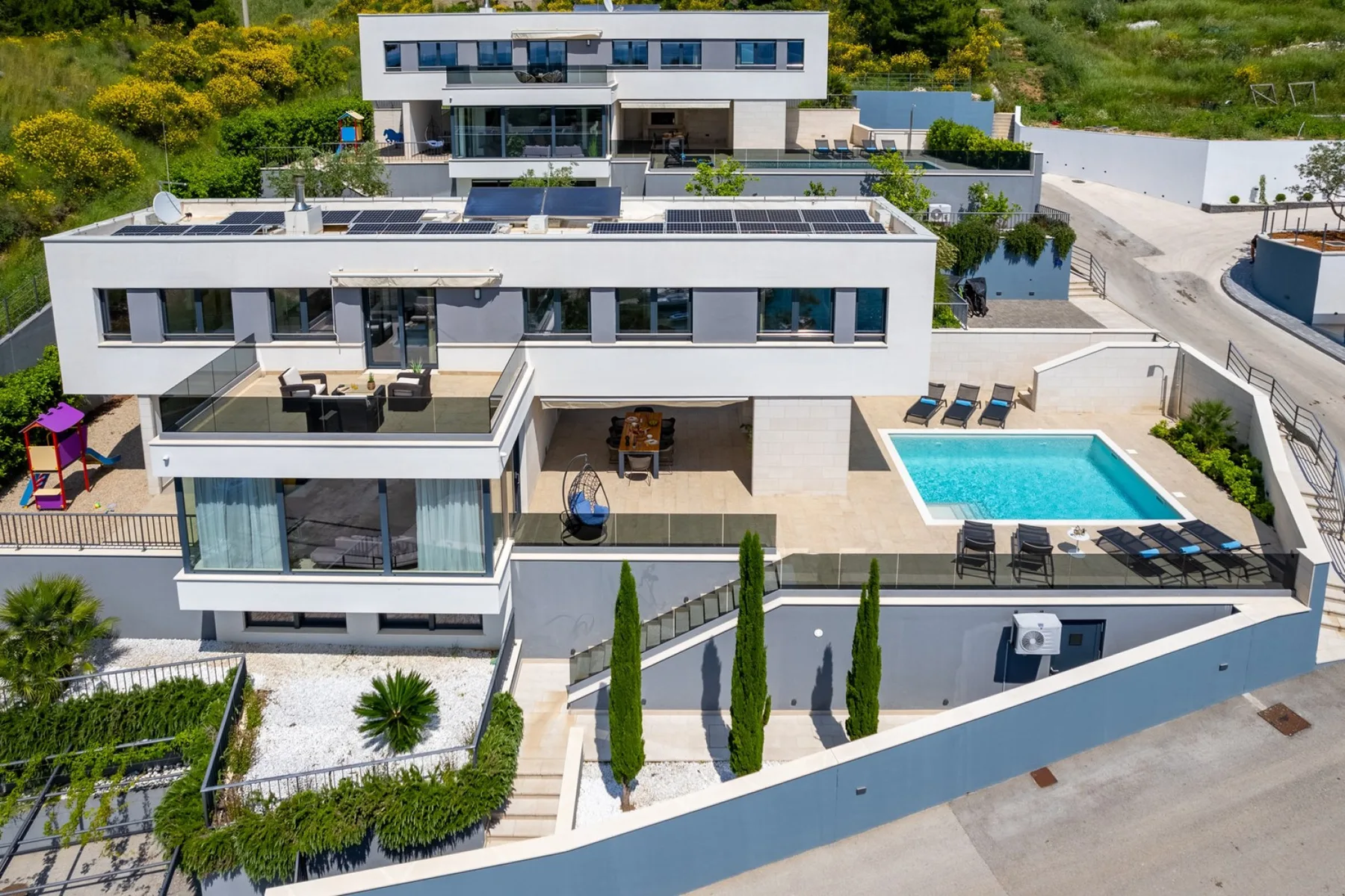 A modern white house with a swimming pool and landscaped grounds.