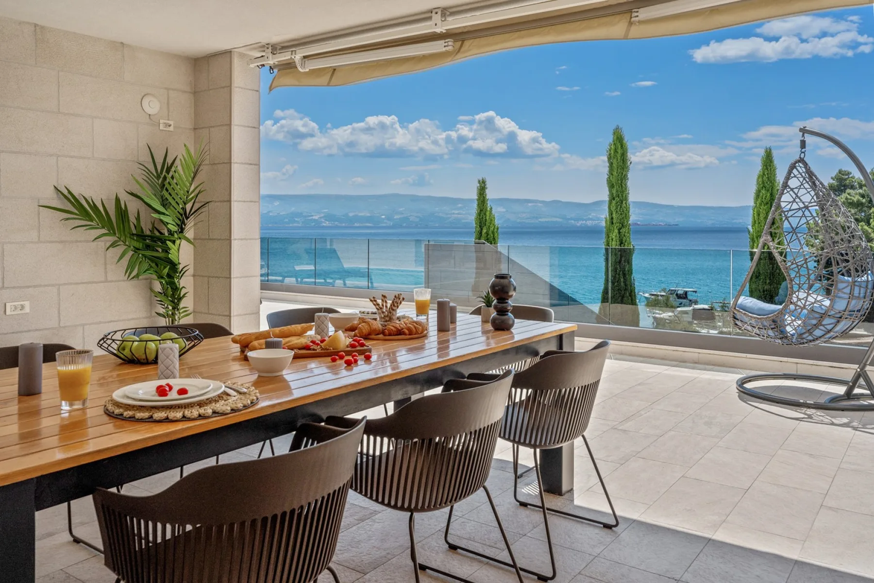 A dining area opens onto a terrace with a view of the sea.