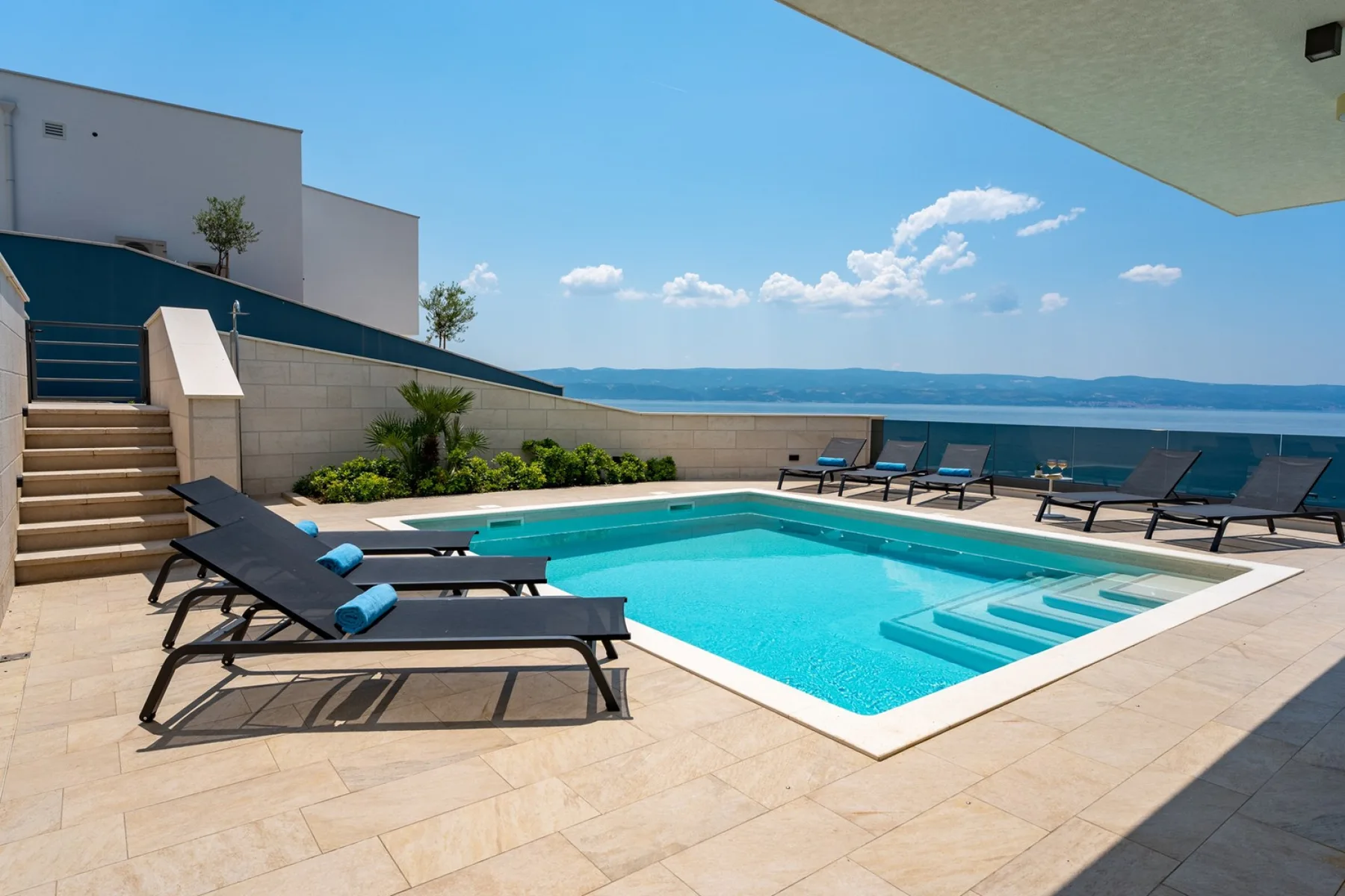 A rooftop pool area with lounge seating and a view of the water.