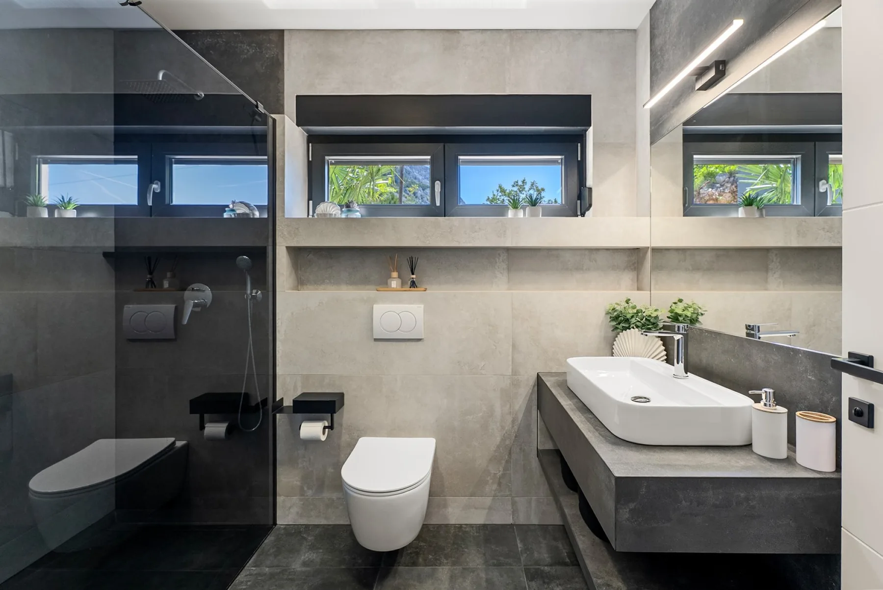 Modern bathroom with a glass-enclosed shower, wall-mounted toilet, and wide vanity beneath a mirror.