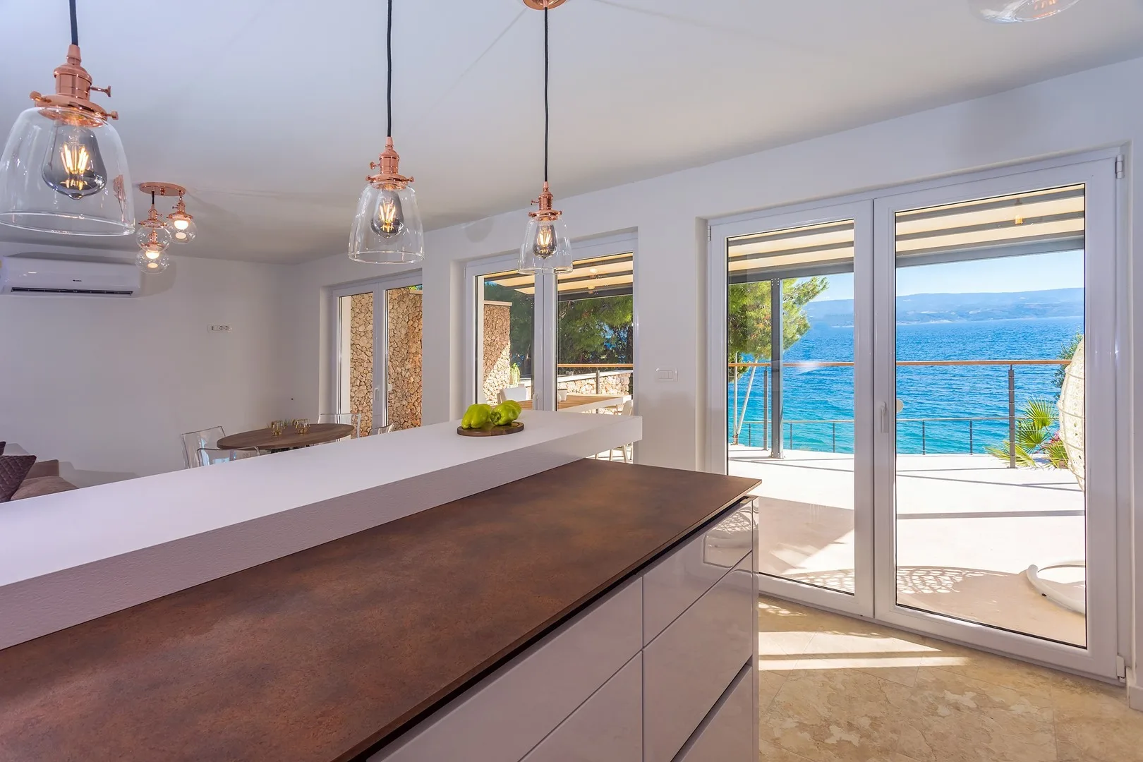 A bright kitchen with a long counter and large windows overlooking the water.