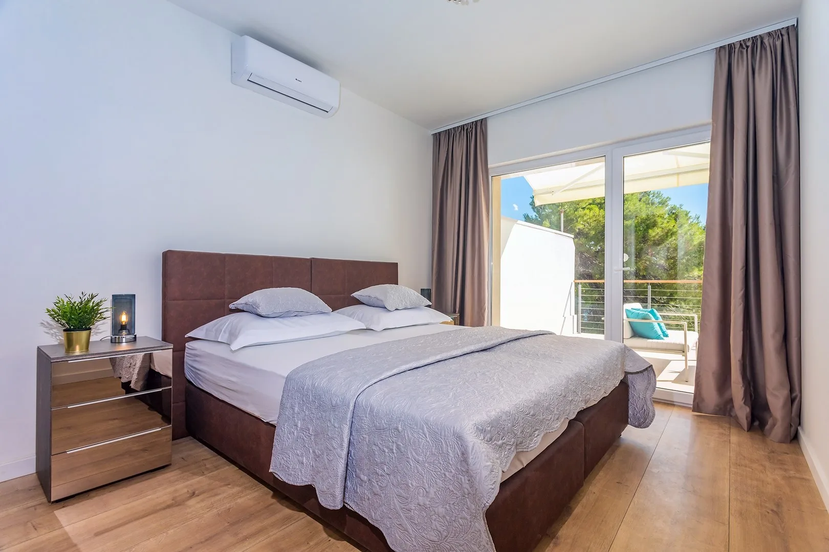 A bedroom with a double bed beside glass doors opening to a balcony.