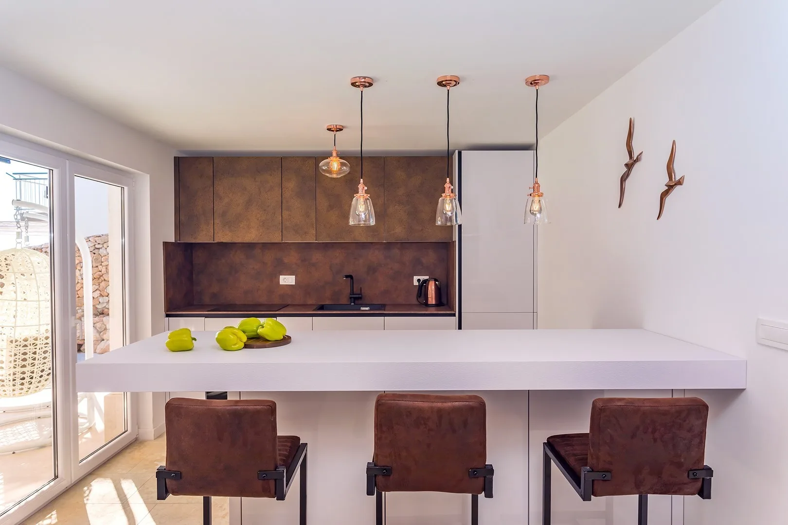 A modern kitchen with a long island and pendant lights above seating.