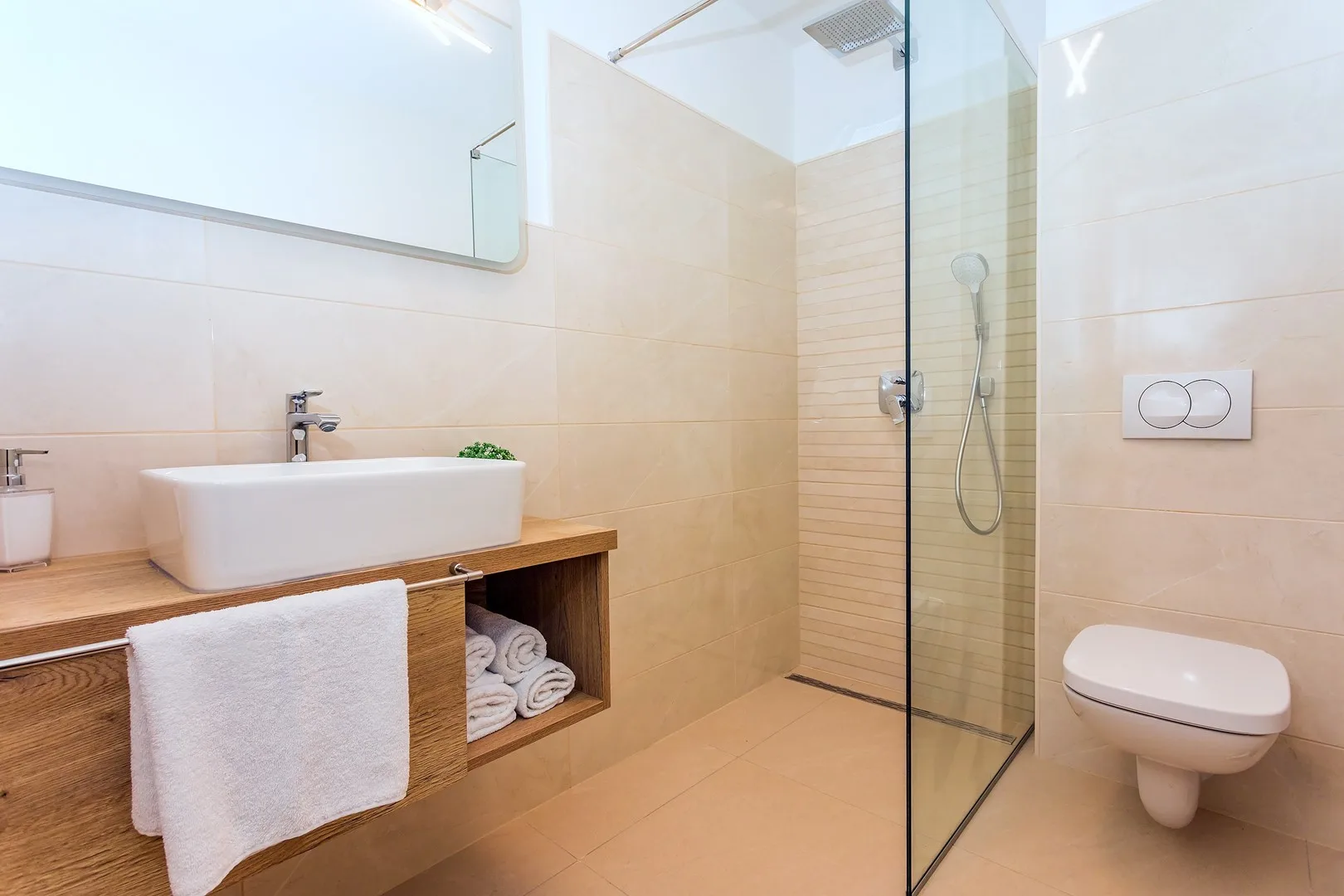 A modern bathroom with a vanity, glass shower, and wall-mounted toilet.