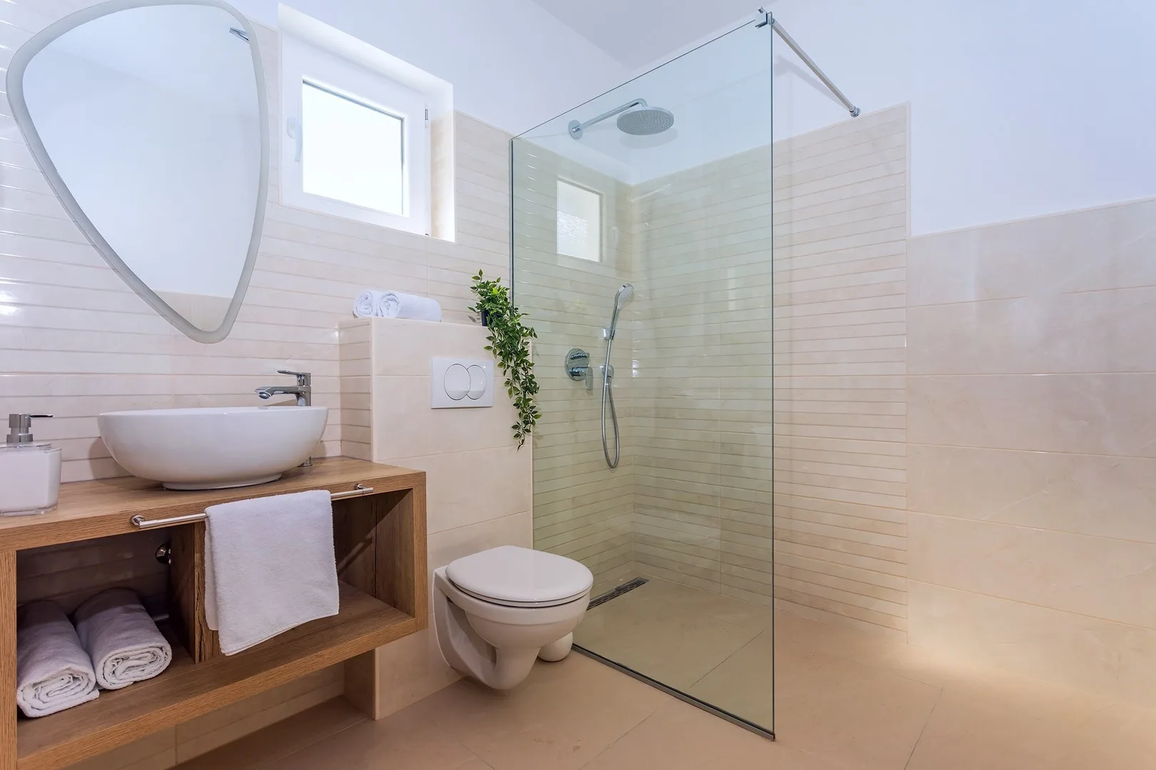 A tiled bathroom with a glass shower, sink, and toilet.