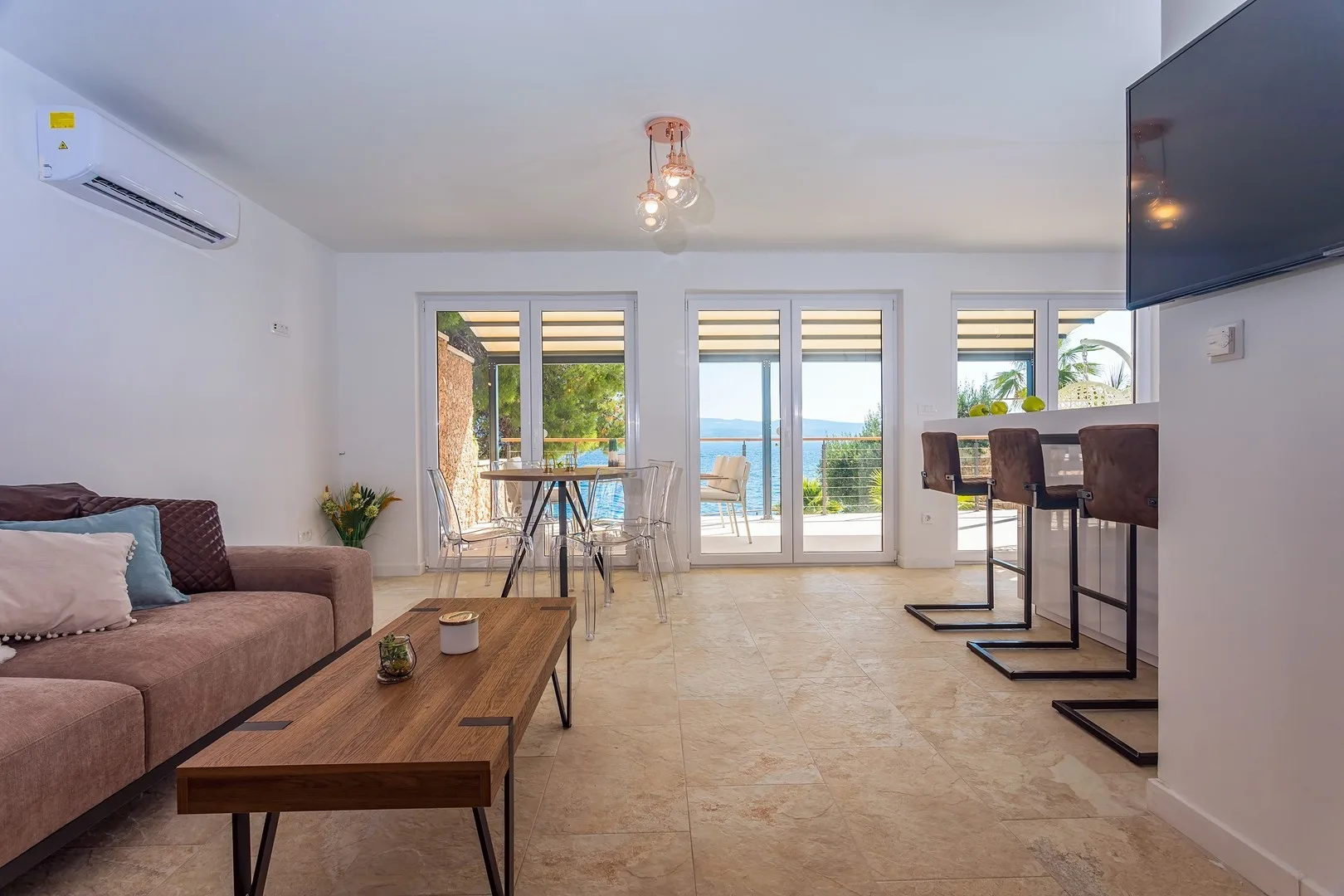 A bright living and dining area opens onto a balcony with a sea view.