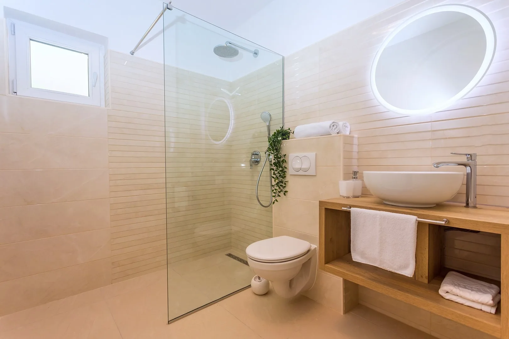 A bright bathroom features a glass shower and a wooden vanity.