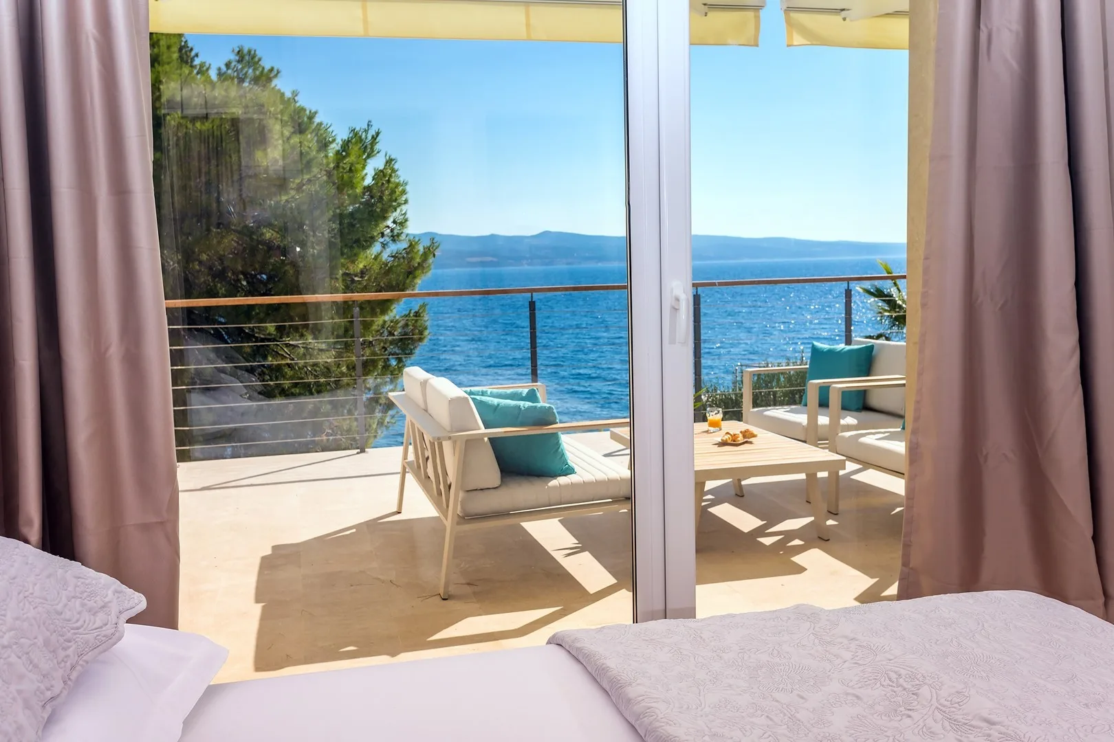 A bright bedroom opens onto a terrace overlooking the sea.