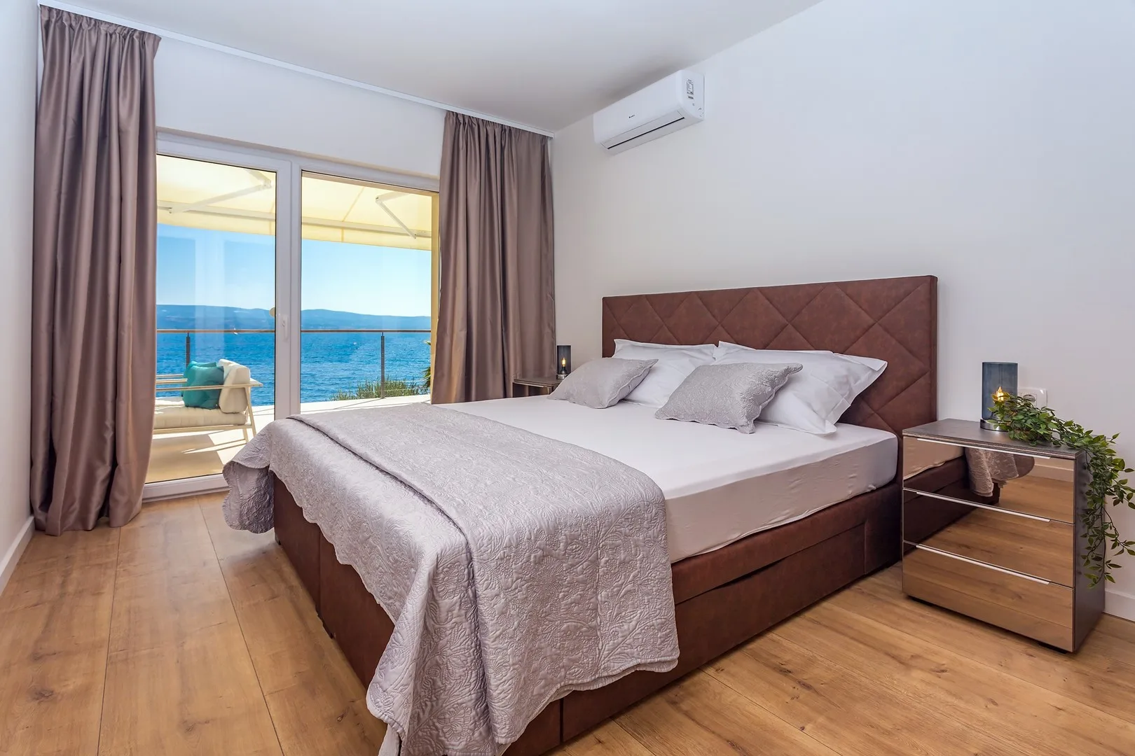 A bedroom with a large bed beside glass doors opening onto a balcony.
