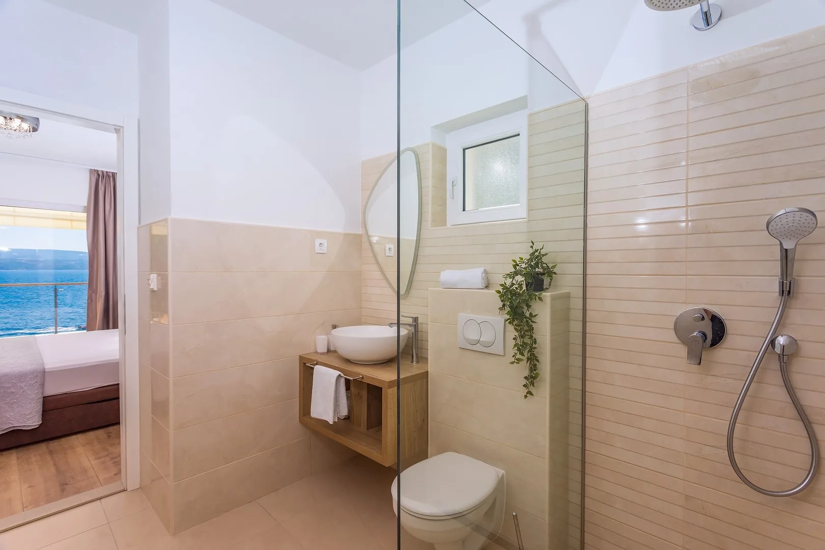 A tiled bathroom with a glass shower partition, sink, and toilet.