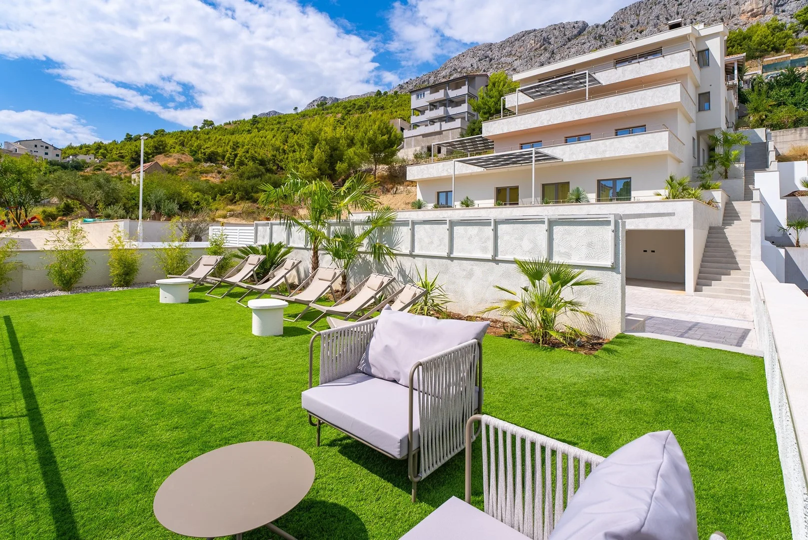 A landscaped outdoor seating area with a green lawn beside a modern building.