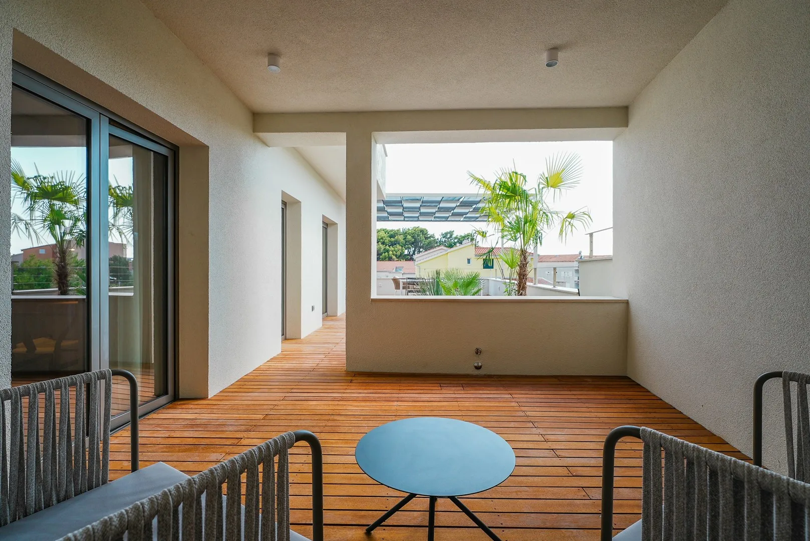 A covered outdoor terrace with wooden decking, seating, and a small table.