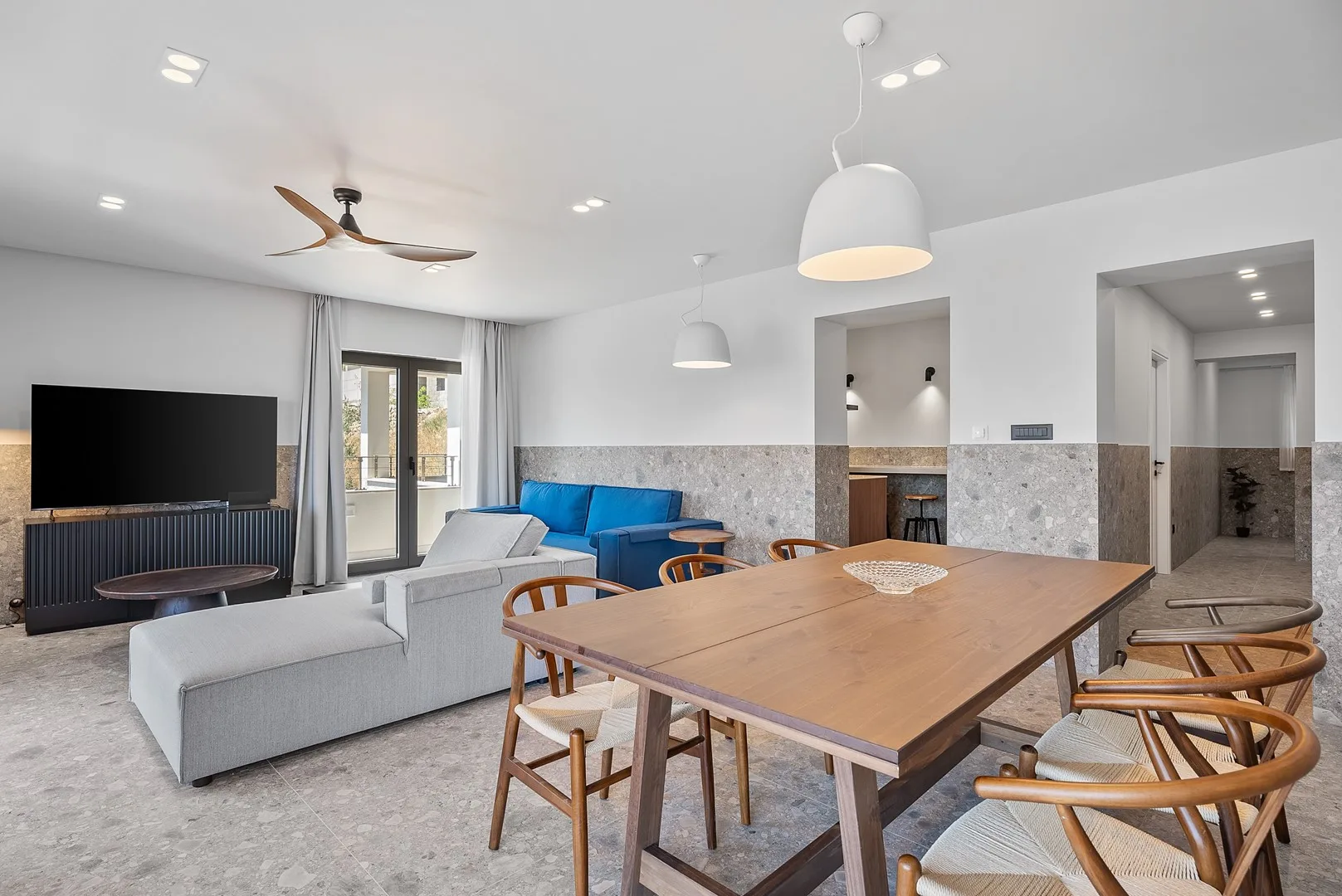 A living and dining area with a gray seating arrangement and a wooden dining table.