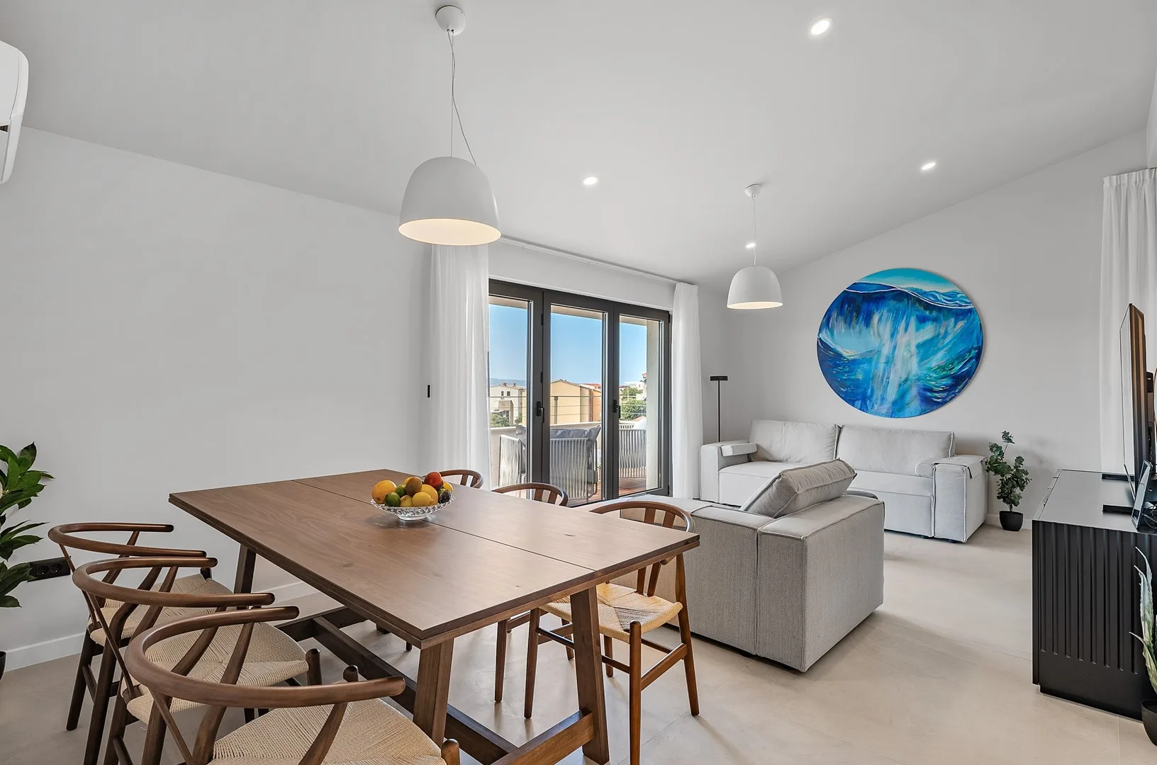 A bright open-plan living and dining area with a large table and seating.
