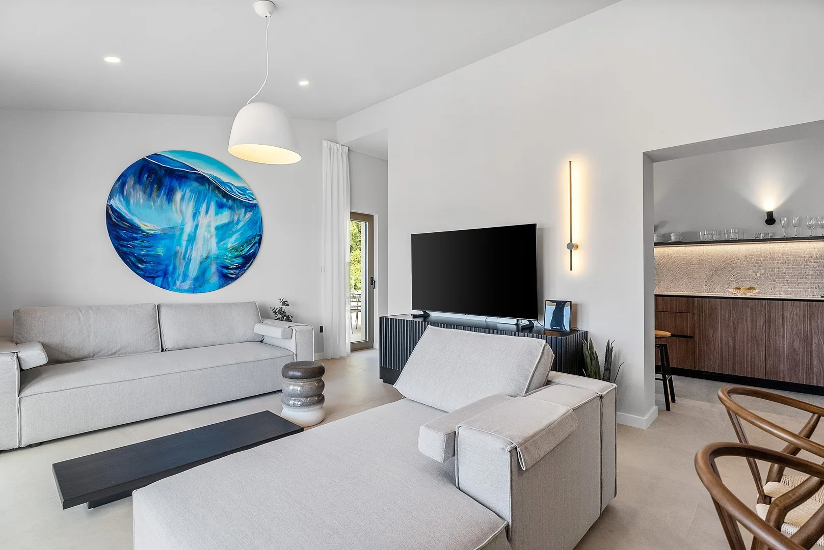 A bright living room with a sectional seating area, television, and blue wall art.