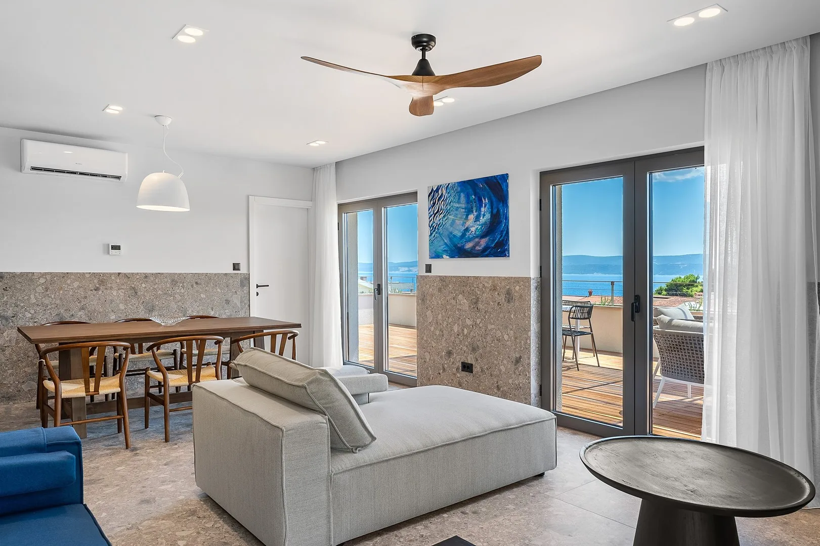 A bright living and dining area opens onto a balcony overlooking the sea.