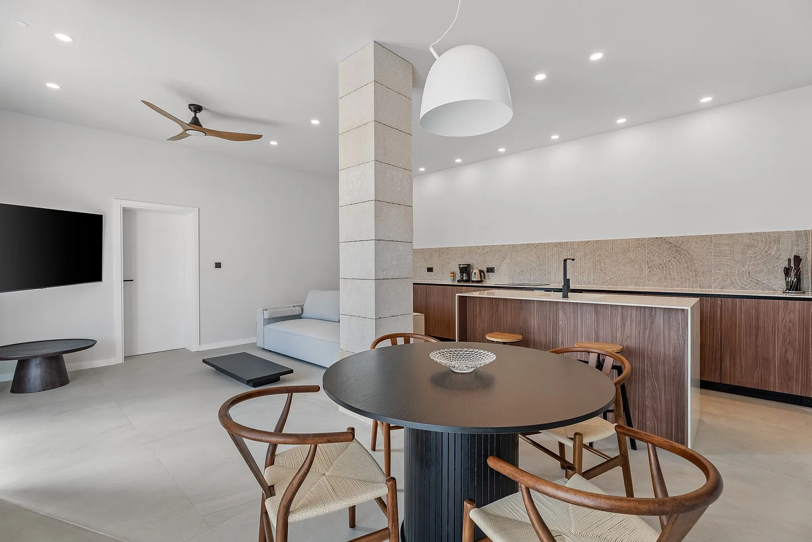 A modern dining and kitchen area with a round table and counter.