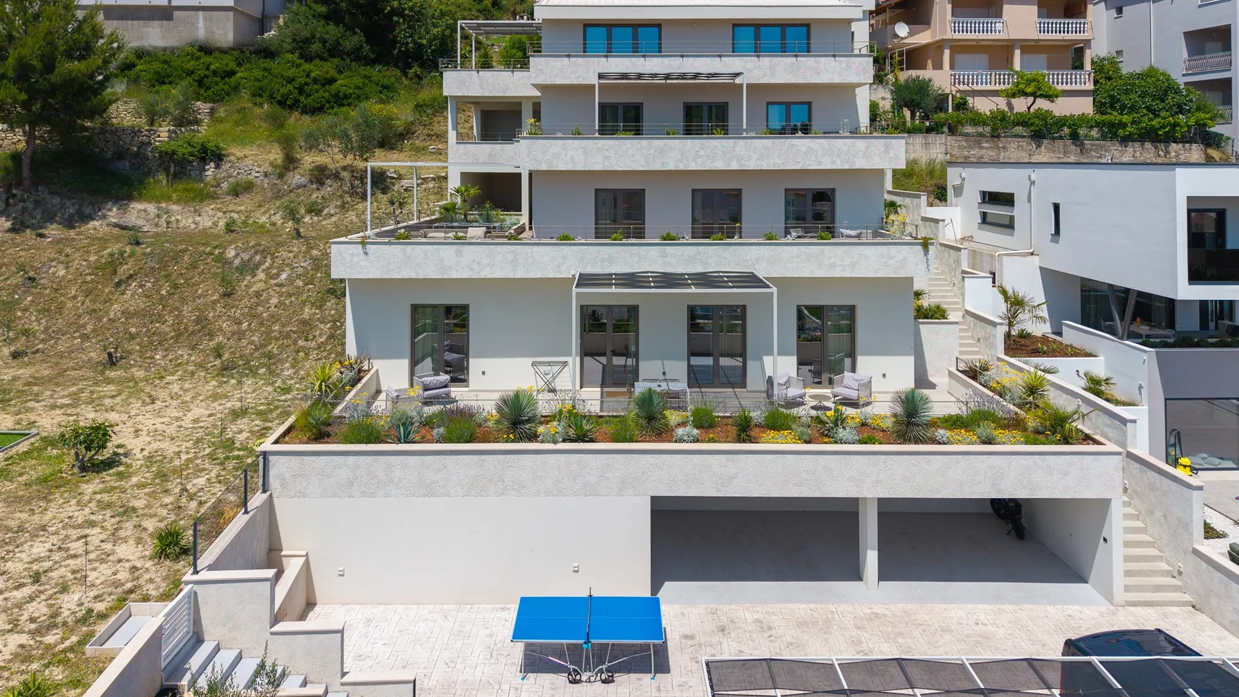 A modern multi-level building with terraces and an open paved area in front.