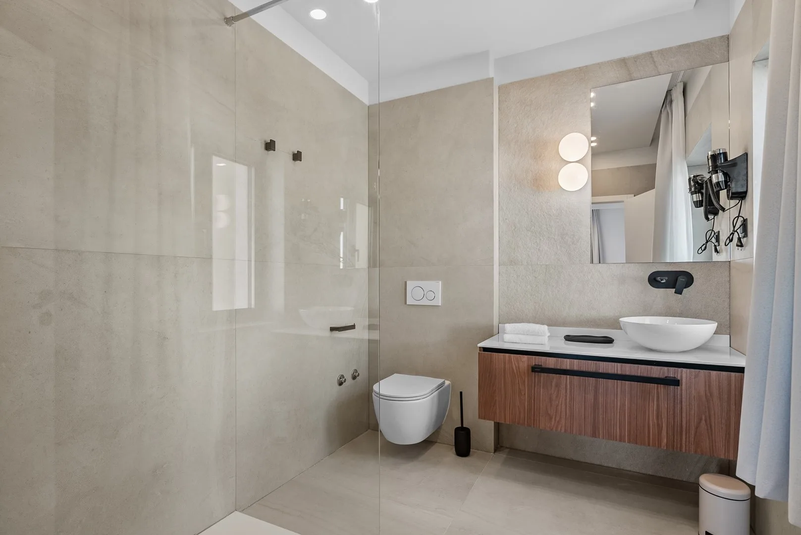 A modern bathroom with a glass shower and a vanity with a vessel sink.