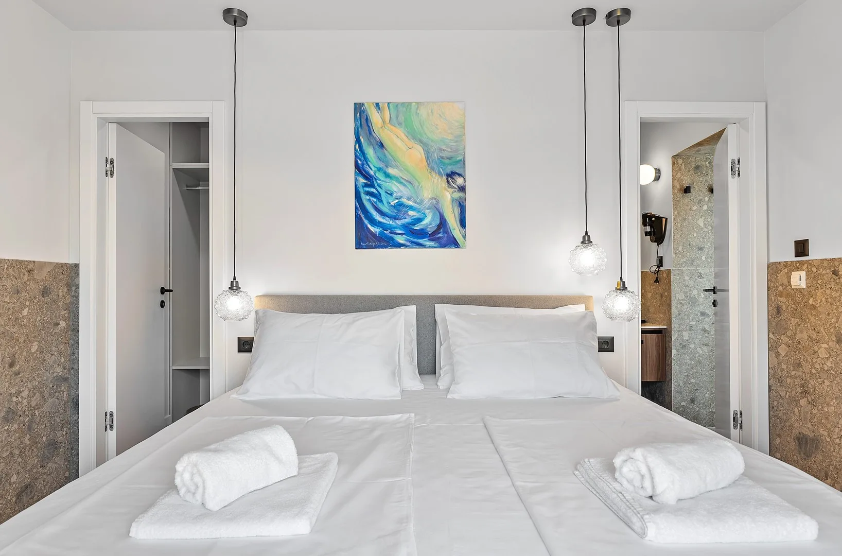 A bedroom with a neatly made bed and colorful artwork above the headboard.