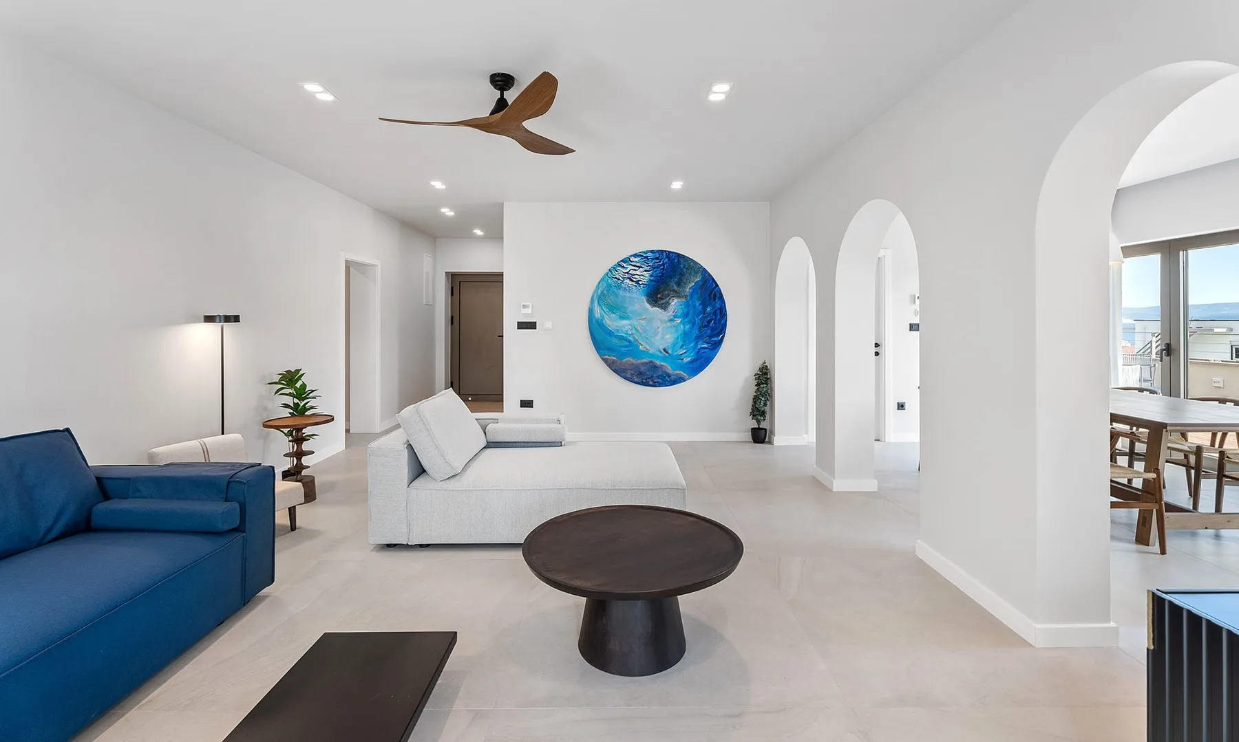 A bright living room with blue and white seating and a large circular wall artwork.